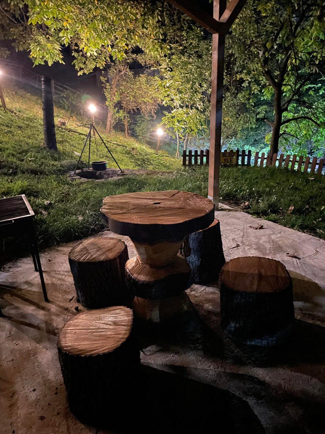 Masa de bușteni cu scăunele din trunchi de copac, noaptea